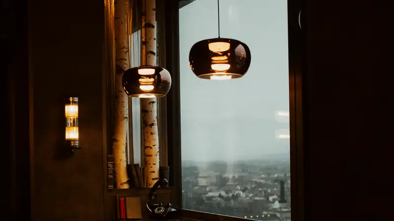 A low hanging lamp over the corner table, the light pooled on the wood and the rest of the room dark around it.