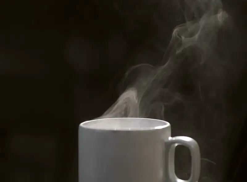A cup brewed to order on the bench, the steam still coming off it against the dark of the room.